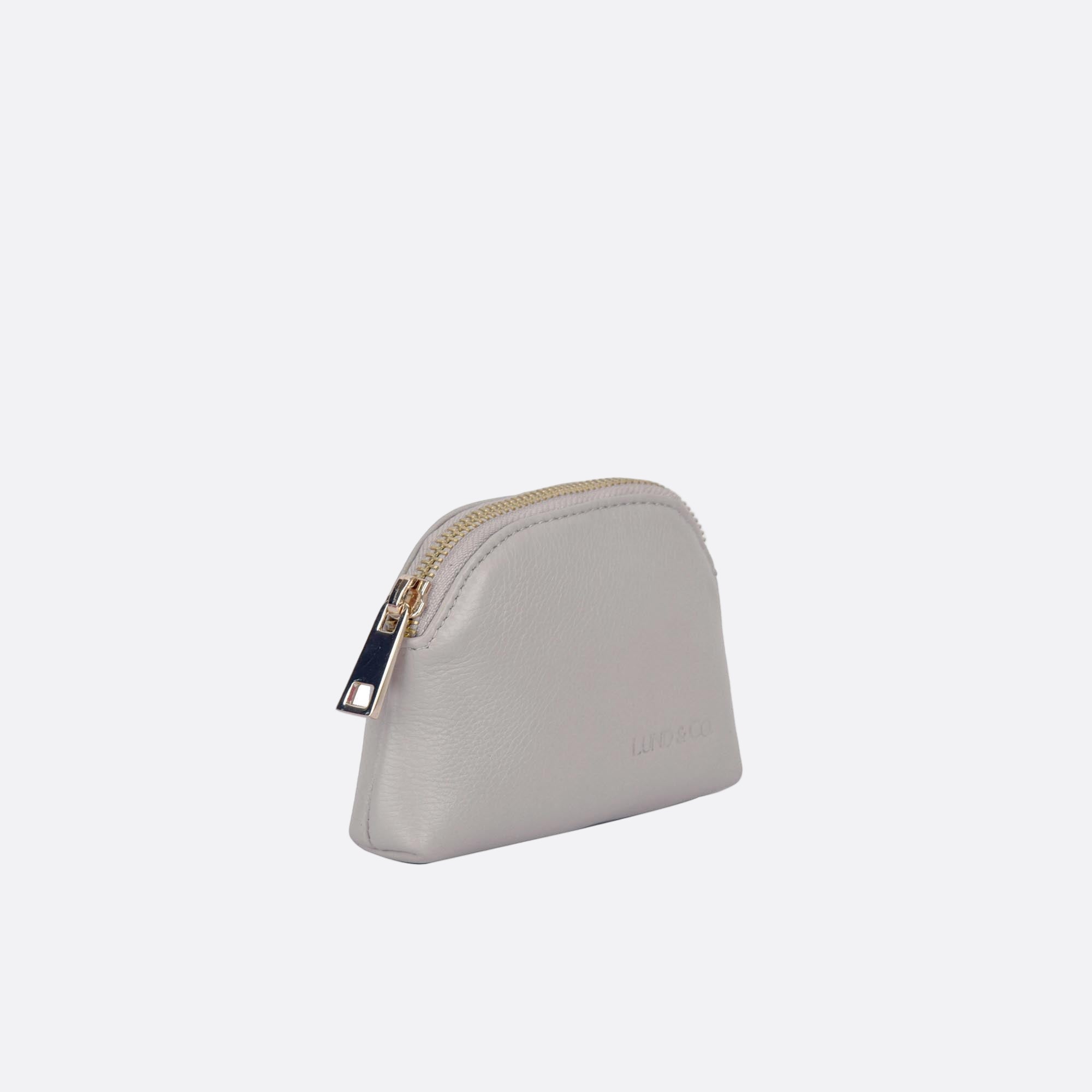 Side angle of LILLA-S beige leather dome purse showing slim profile and zip closure